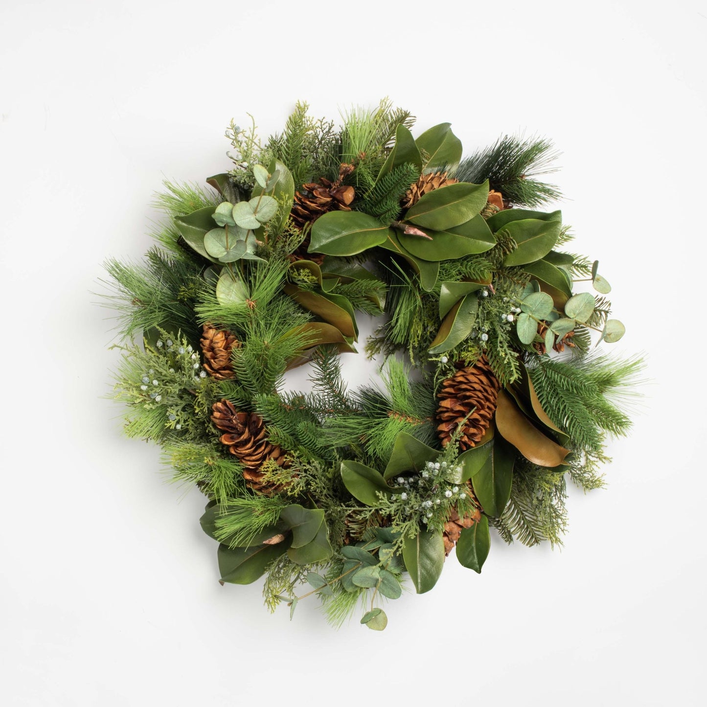 Green Christmas wreath with pine cones and leaves on a white background