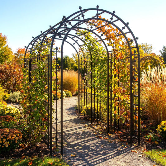 h potter black metal arched garden arbor trellis installed in a landscaped garden with autumn foliage, a gravel path, and plants on both sides.