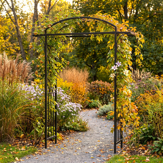 h potter brand black metal garden arch with climbing vines and yellow autumn leaves, framing a gravel path in a lush garden with ornamental grasses and flowers.