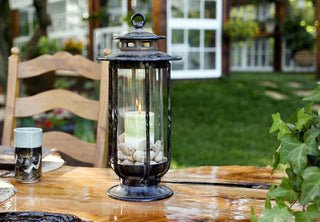 H Potter brand cast iron metal decorative candle lantern with hand-blown glass on a table outside