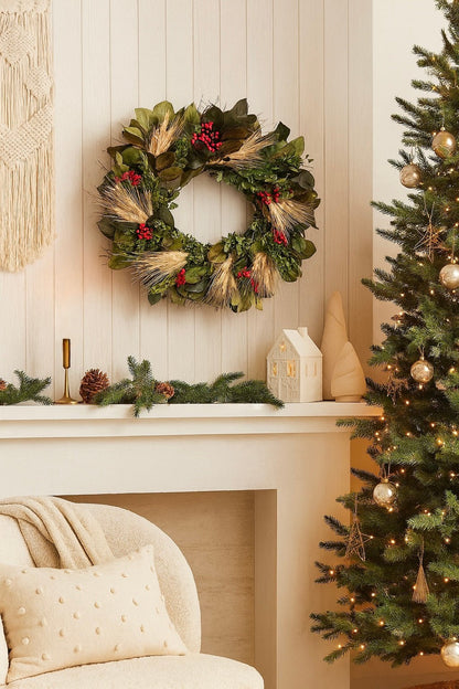 Decorative Christmas wreath on a mantelpiece with a lit Christmas tree in the corner.