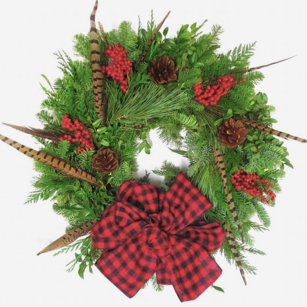 Christmas wreath with red plaid bow, pinecones, and feathers on a white background