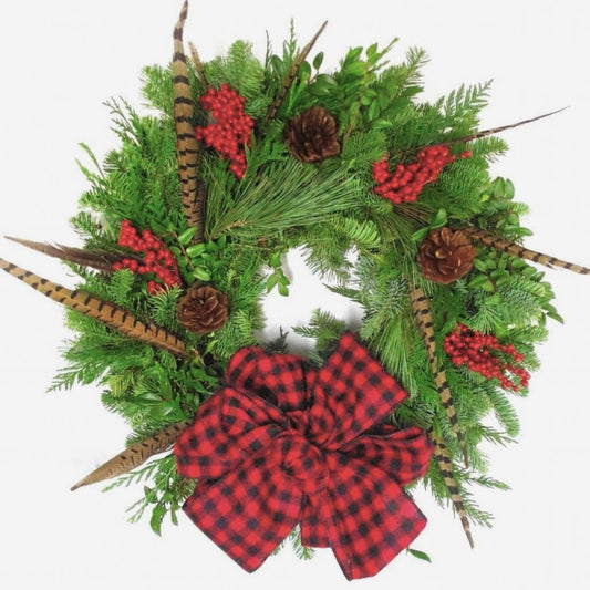 Christmas wreath with red plaid bow, pinecones, and feathers on a white background