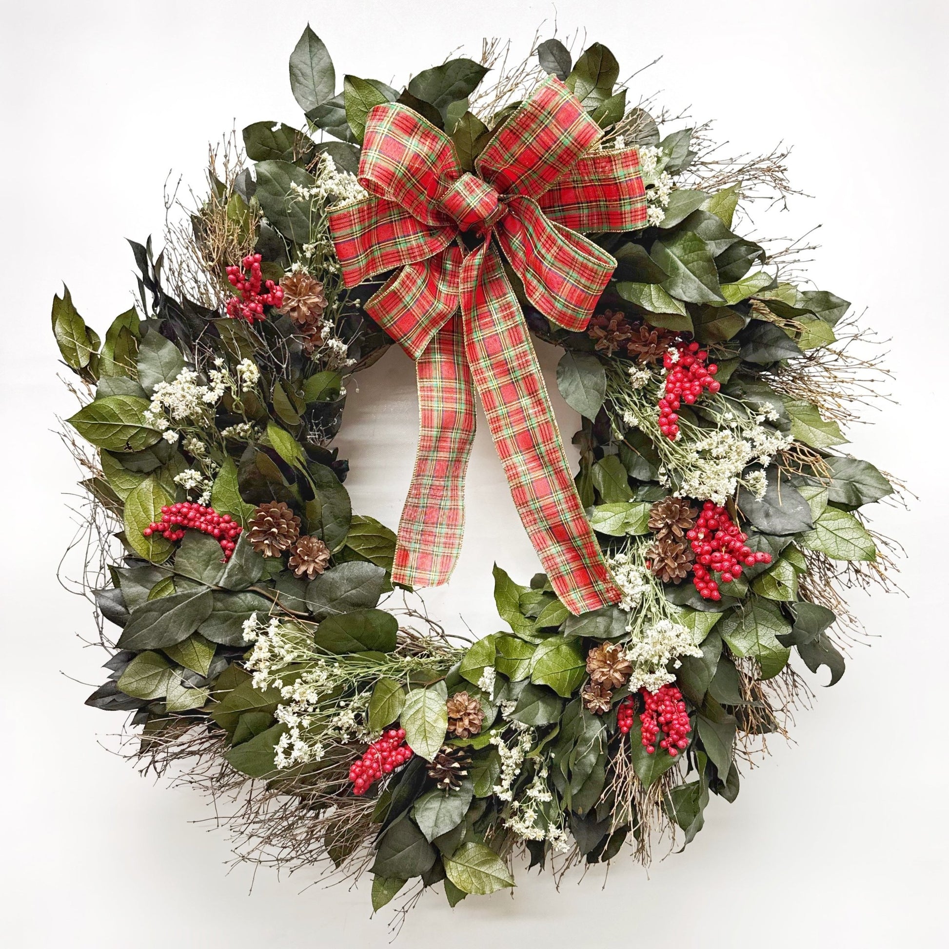 Christmas wreath with plaid bow, red berries and pinecones on a white background
