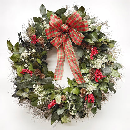 Christmas wreath with plaid bow, red berries and pinecones on a white background