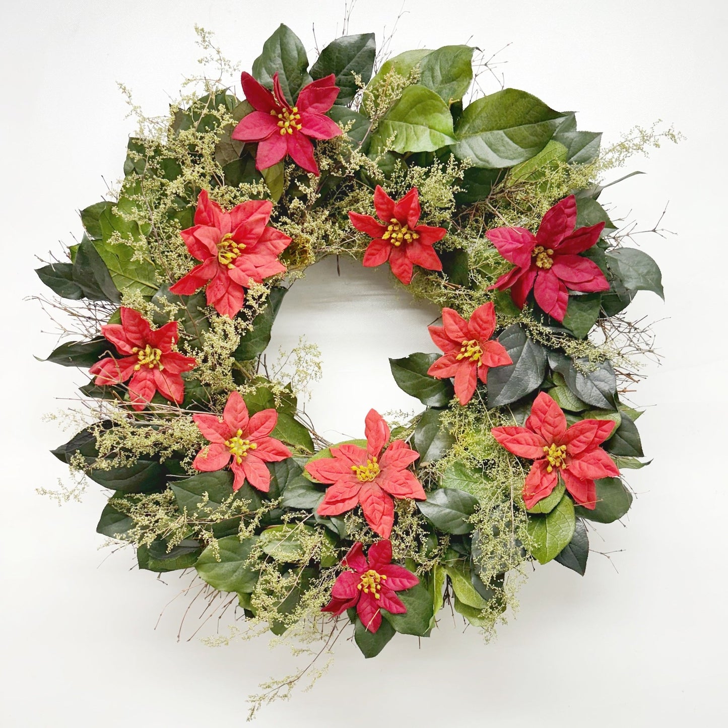 Christmas wreath with poinsettia flowers and green leaves on white background
