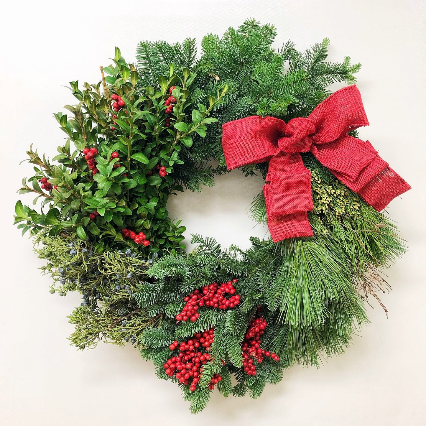 Christmas wreath with red berries and a red bow on a white background