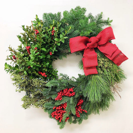 Christmas wreath with red berries and a red bow on a white background