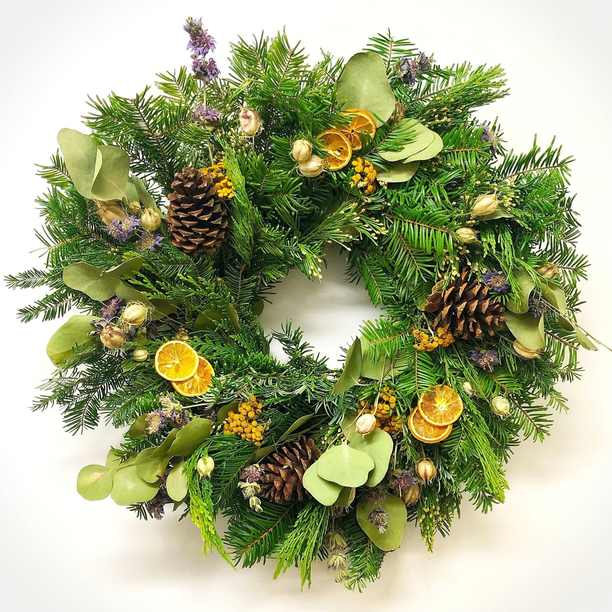 Decorative Christmas wreath with orange slices and pinecones and purple flowers on a white background