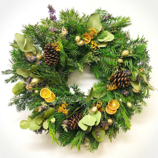 Decorative Christmas wreath with orange slices and pinecones and purple flowers on a white background