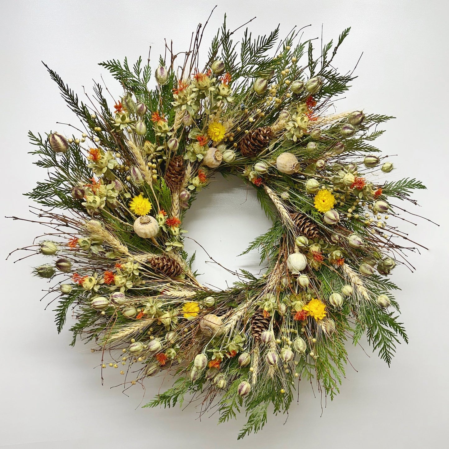 Autumn bramble wreath on wall—handmade H Potter dried botanicals: twigs, cedar, wheat, safflower, strawflower, pine cones.