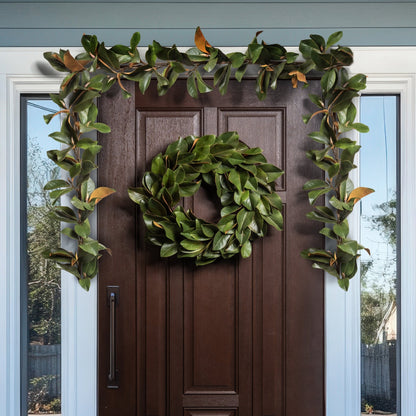 Decorative green wreath and garland on a brown door with glass panels.