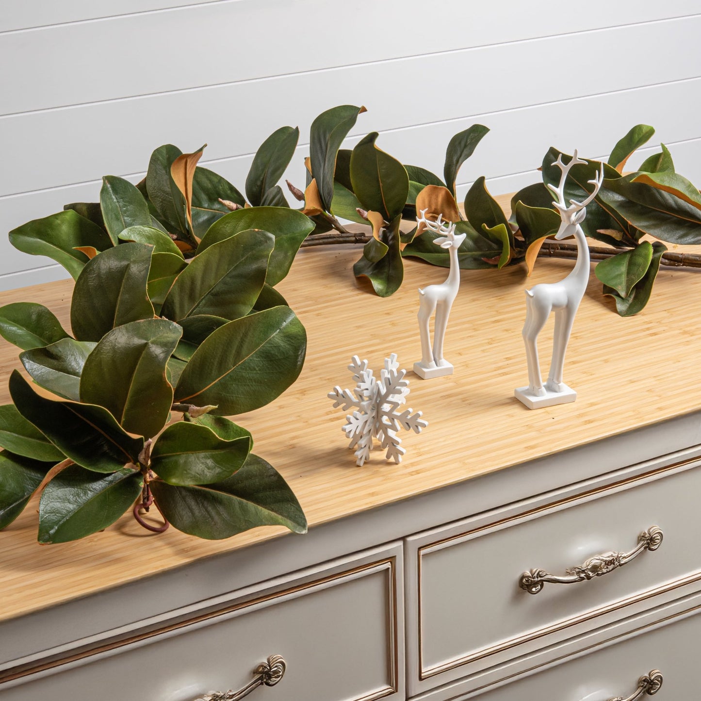 decorative holiday magnolia garland on a set of drawers with holiday decorations