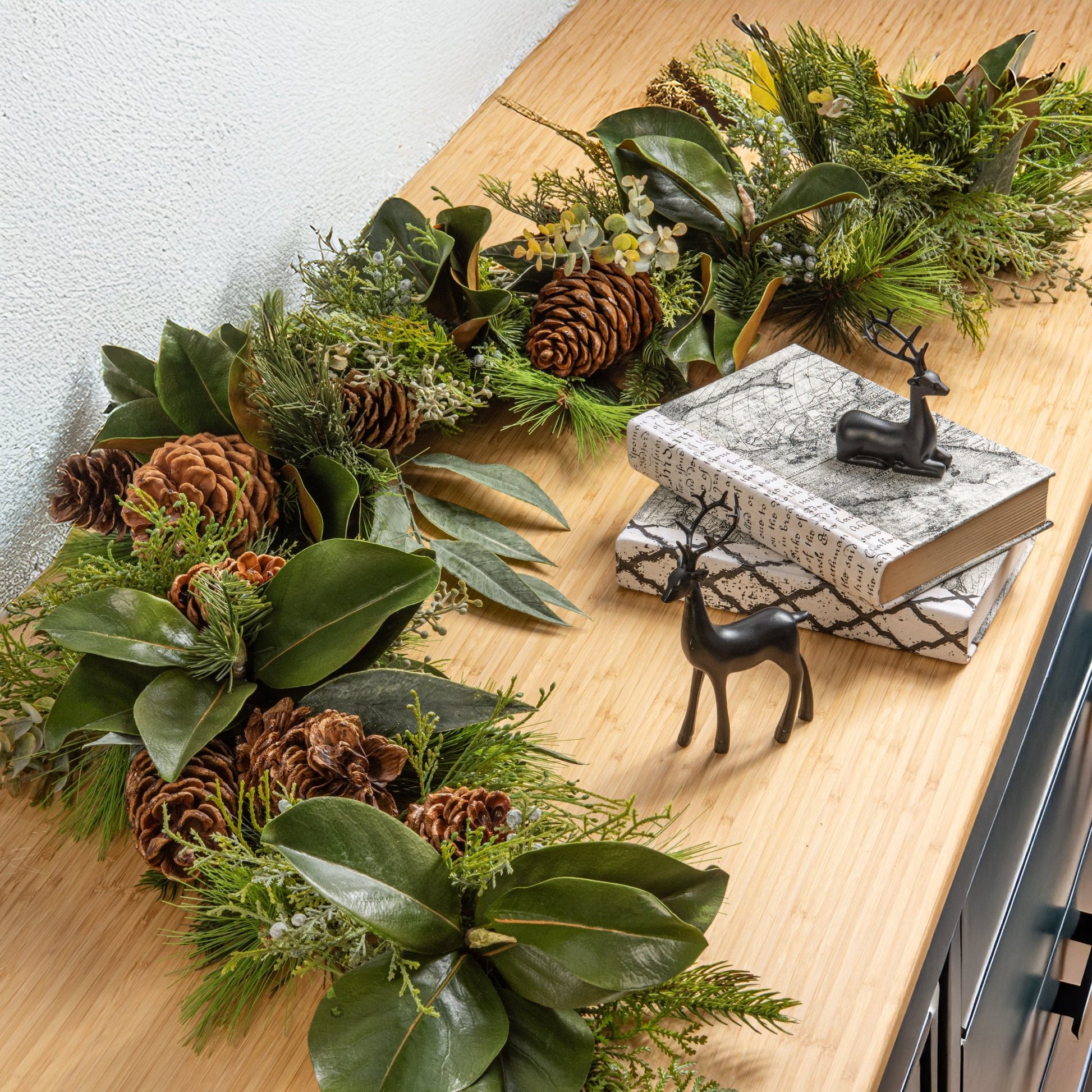 decorative christmas wreath with pinecones and greenery on a set of cabinets with holiday decor