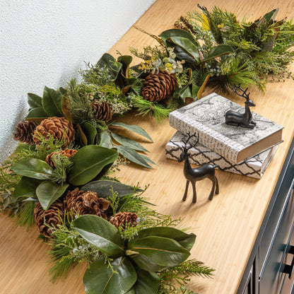 decorative christmas wreath with pinecones and greenery on a set of cabinets with holiday decor