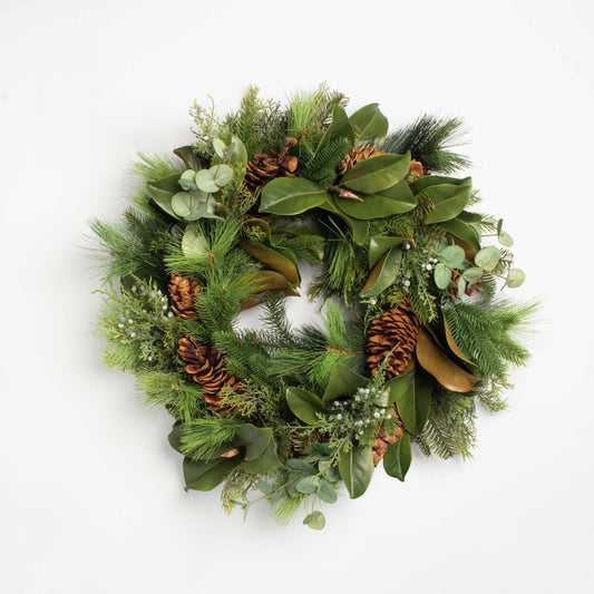 Green Christmas wreath with pine cones and leaves on a white background