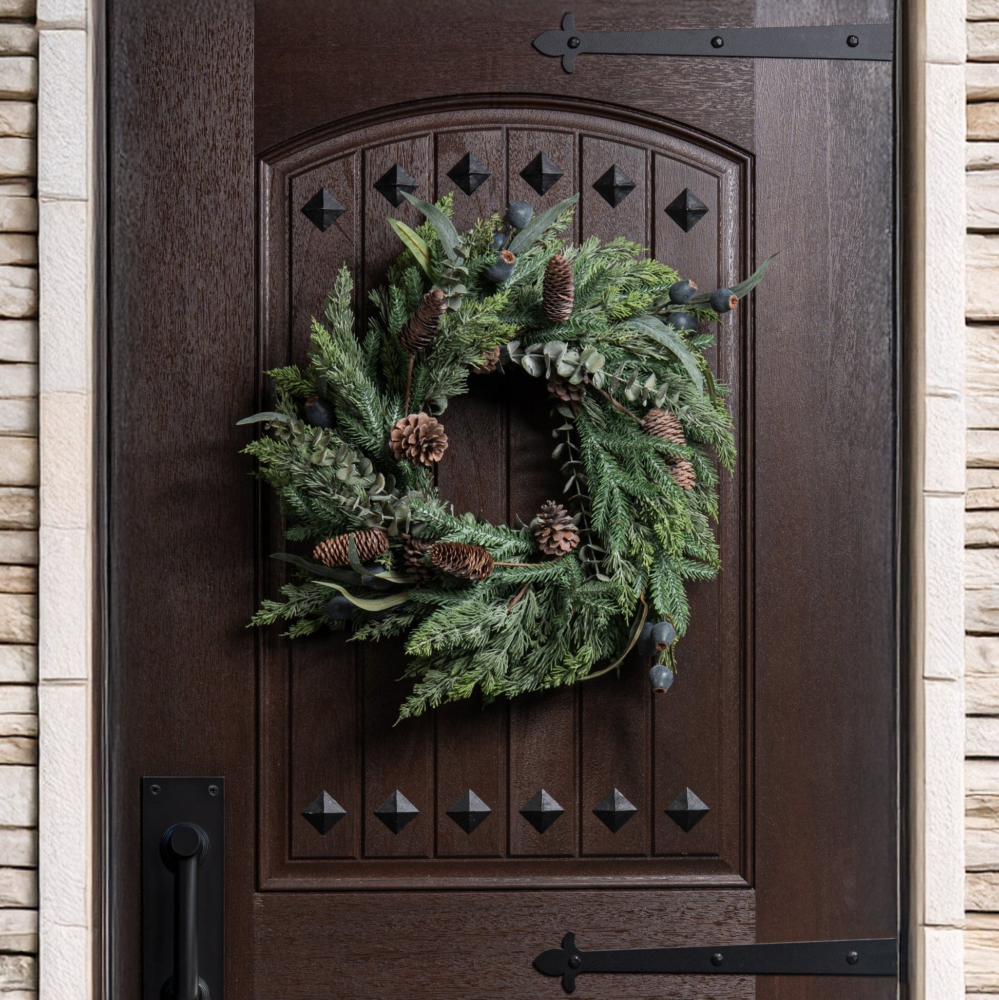 green eucalyptus holiday wreath with pinecones on a wooden door