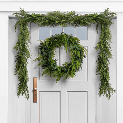 green cedar christmas wreath and garland on a white door
