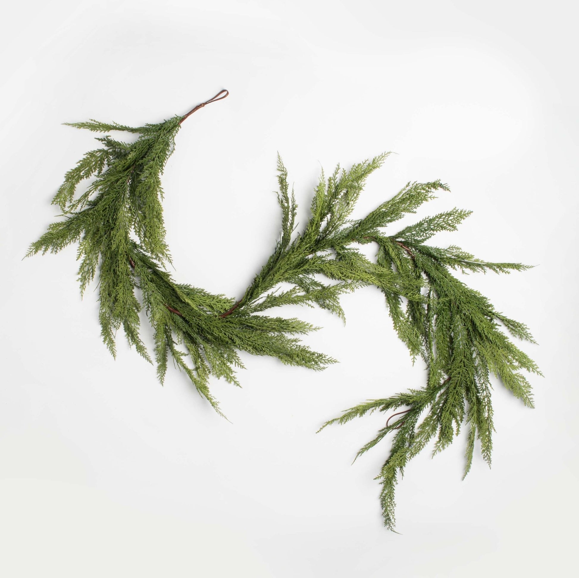 decorative holiday garland cedar and pine accents on a white background