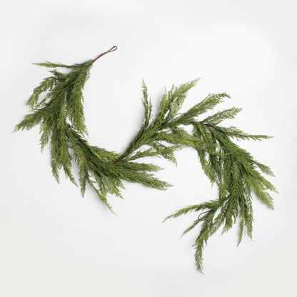 decorative holiday garland cedar and pine accents on a white background