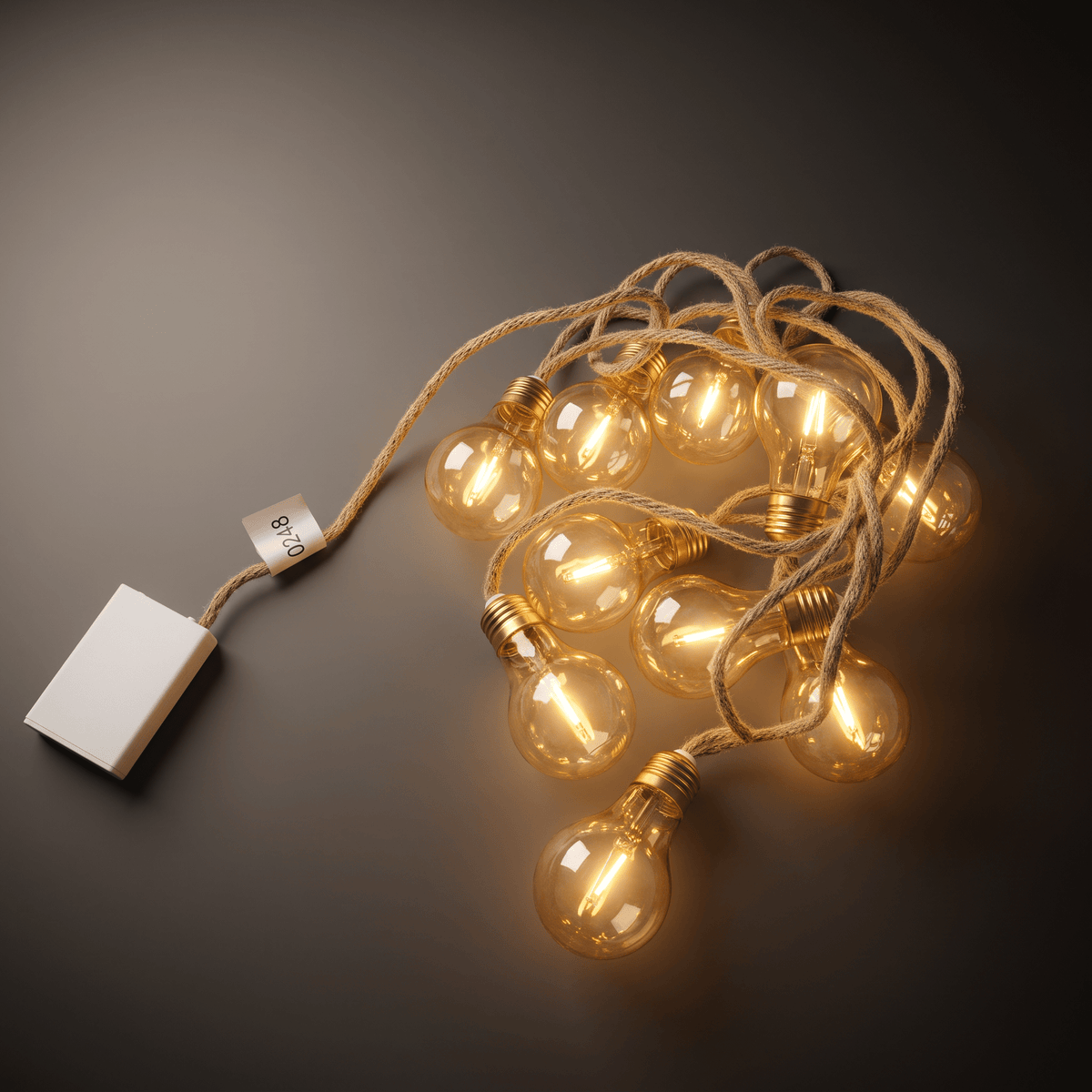 h potter galaxy led lights with warm white LED string light with multiple clear glass globe bulbs on a twisted jute cord, attached to a white rectangular power block, photographed on a dark gray background.
