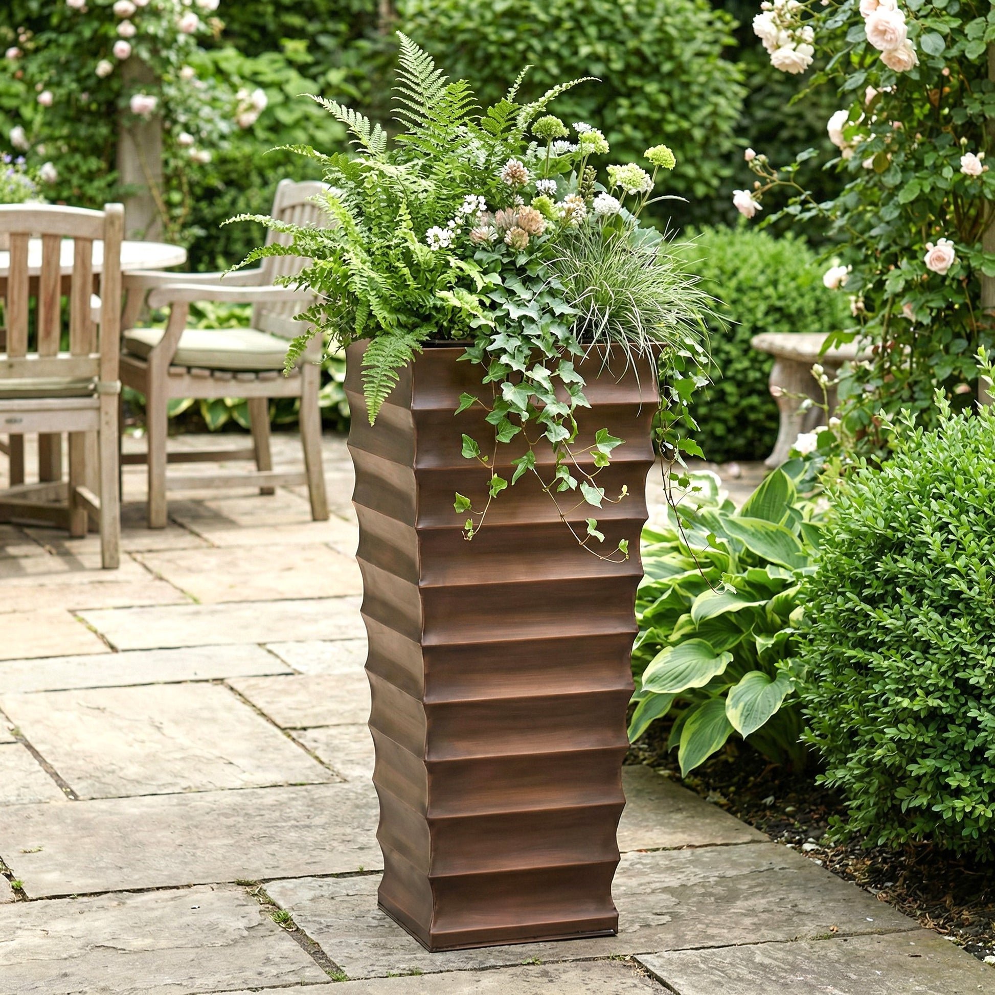h potter tall antique copper garden planter on stone patio with green plants