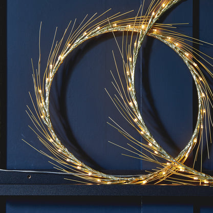 Close view of the Celeste wreath's fine gold-toned spokes and the warm LEDs running around its ring