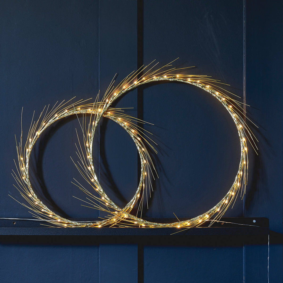 H Potter Celeste lighted wreath set, large and small rings lit on a deep navy panel wall