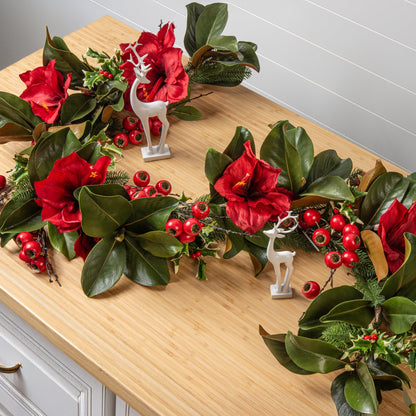 Decorative wreath with red flowers and green leaves on a wooden surface.