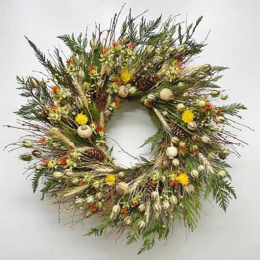 Autumn bramble wreath on wall—handmade H Potter dried botanicals: twigs, cedar, wheat, safflower, strawflower, pine cones.