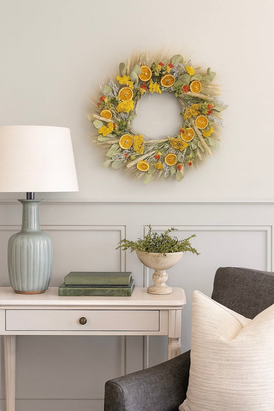 H Potter dried golden citrus wreath with eucalyptus, tansy, nigella, lemon mint, pine cones, orange slices on living room wall