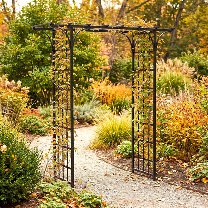 H Potter black metal garden archway with climbing ivy, situated on a gravel path in a lush autumn garden with orange and green foliage.