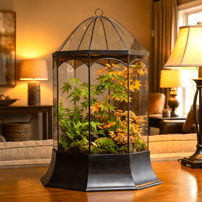 H Potter brand hexagonal glass terrarium filled with green and orange foliage, displayed on a wooden table in a warmly lit living room.