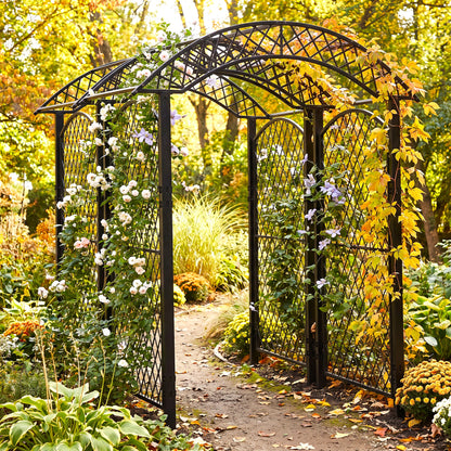 h potter brand black metal arched garden trellis with lattice panels, shown in a lush garden setting with climbing white and purple flowers, autumn foliage, and a dirt path.