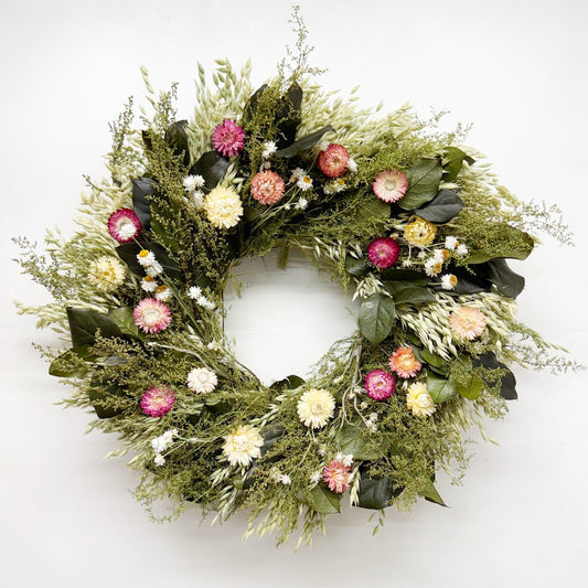 Floral wreath with greenery and colorful flowers on a white background