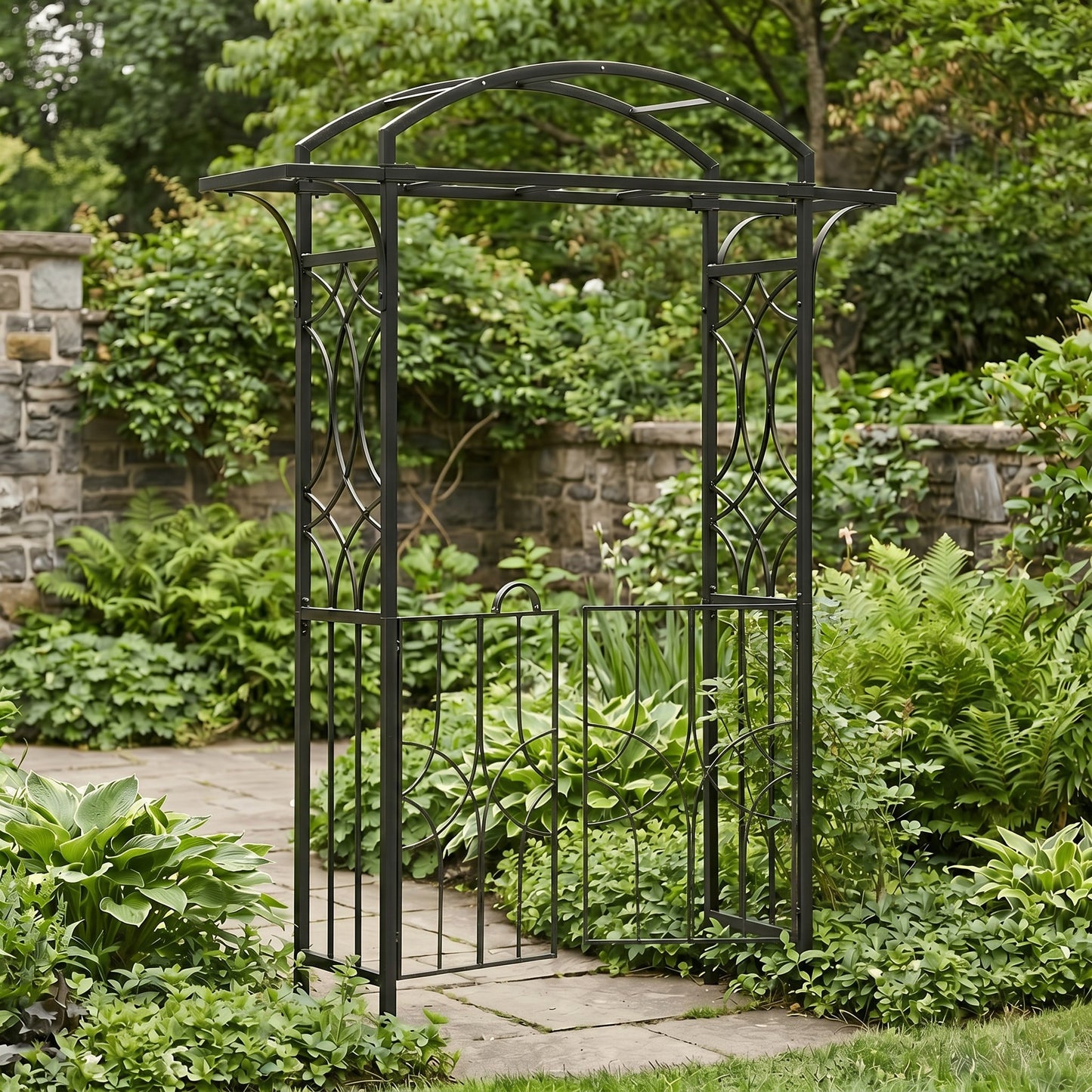 H Potter black metal garden archway in a lush garden setting with stone pathway and stone wall.