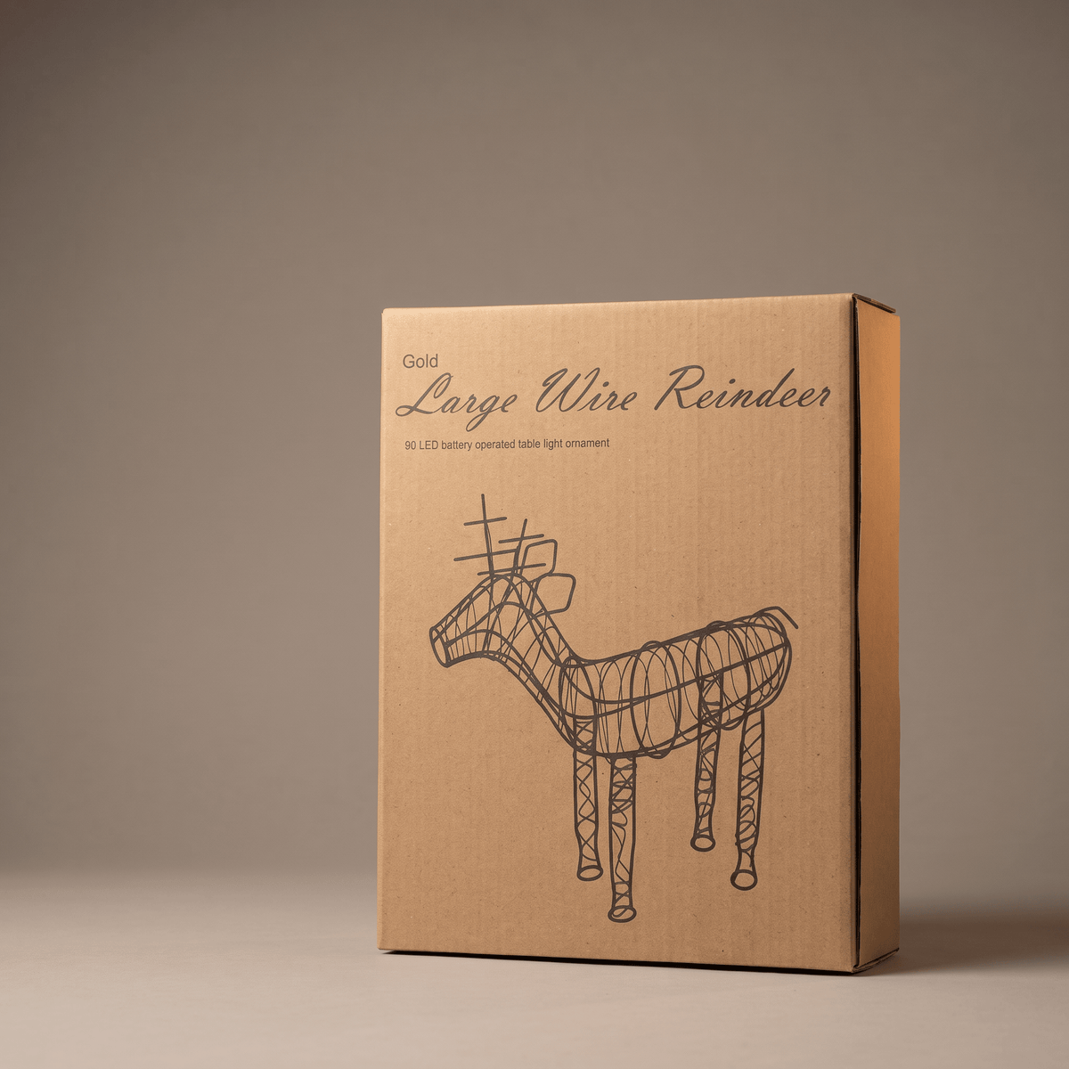 A brown cardboard product box for a 'Gold Large Wire Reindeer' LED ornament, featuring a black line art illustration of the ornament on the front, set against a neutral warm gray background.