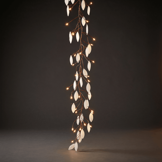 A vertical decorative string lights with white leaf-shaped lights and small warm white bulbs on a dark brown wire, photographed against a dark gray studio background.