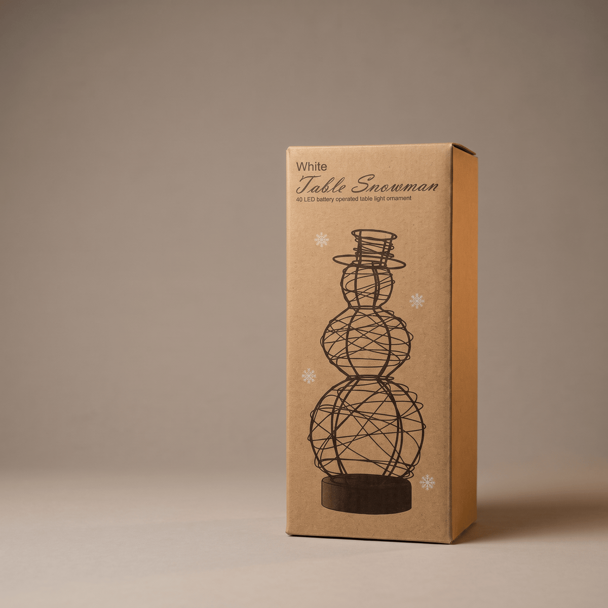 A tall rectangular kraft paper box standing upright on a neutral beige studio background. The box is printed with the words 'White Table Snowman' and a black line drawing of a snowman made of wire spheres on a base.