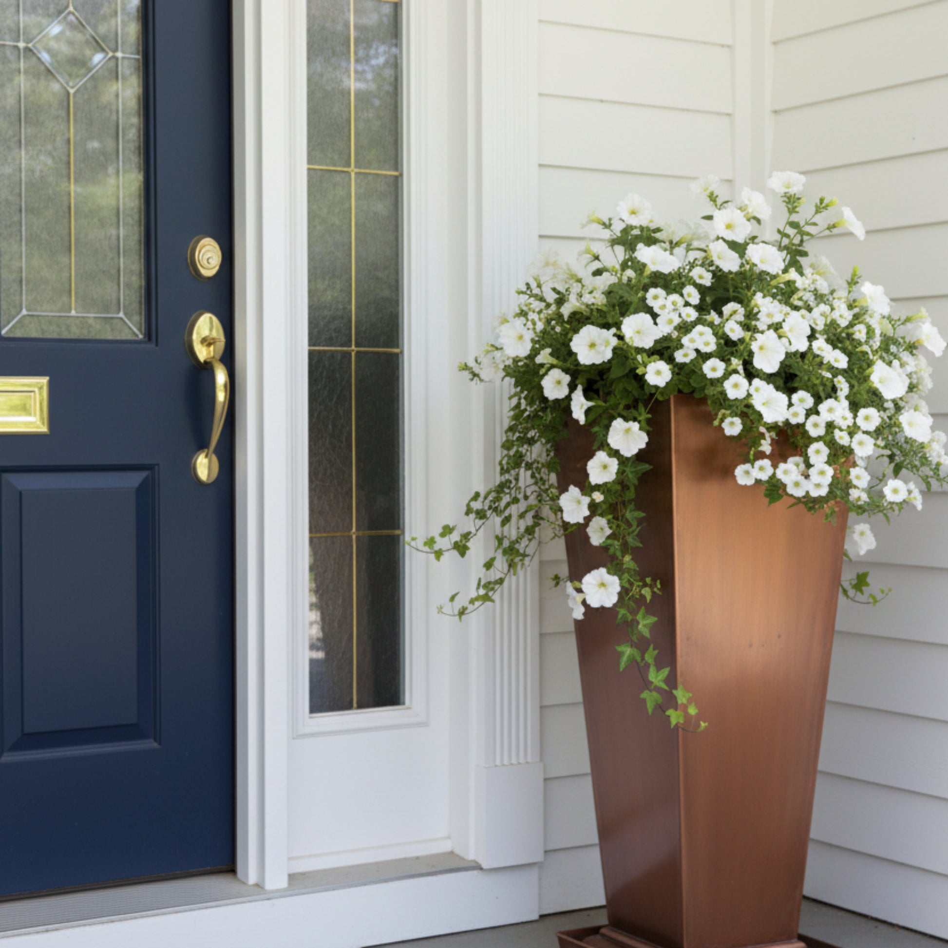 H Potter large outdoor planter in antique copper finish at front door with white flowers