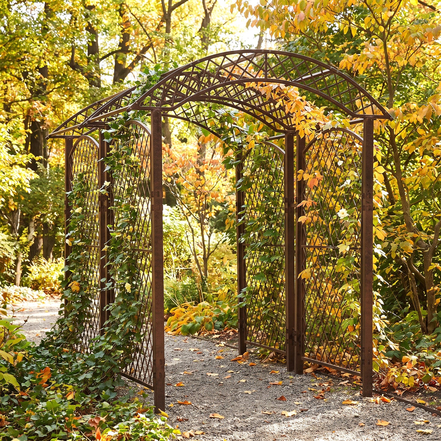 H Potter brand dark brown metal arched garden trellis with lattice panels, shown in a lush autumn garden with yellow and orange foliage.
