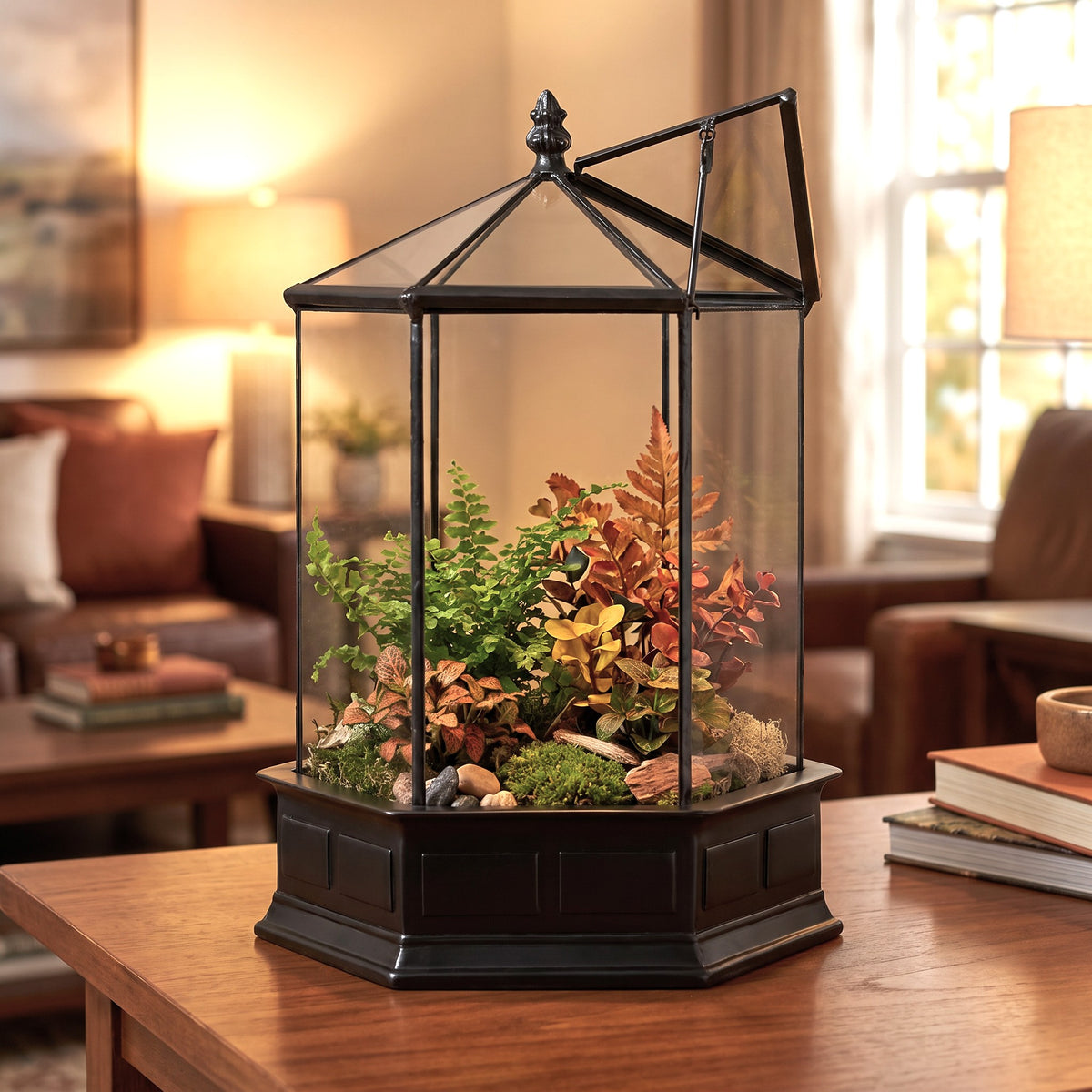h potter brand hexagonal glass terrarium filled with green and autumn-colored plants, moss, and small stones, displayed on a wooden table in a warmly lit living room.