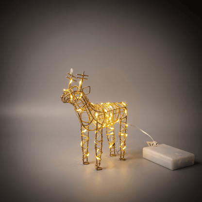Small gold wire-frame reindeer Christmas light sculpture with warm white LED lights, shown standing next to its white power battery on a dark gray gradient background.