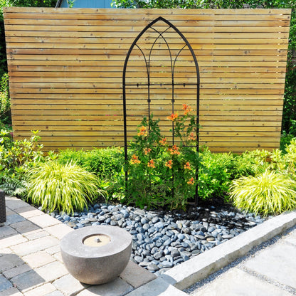 H Potter large black gothic wrought iron garden trellis, freestanding outdoors in a flower garden with landscape rock accents