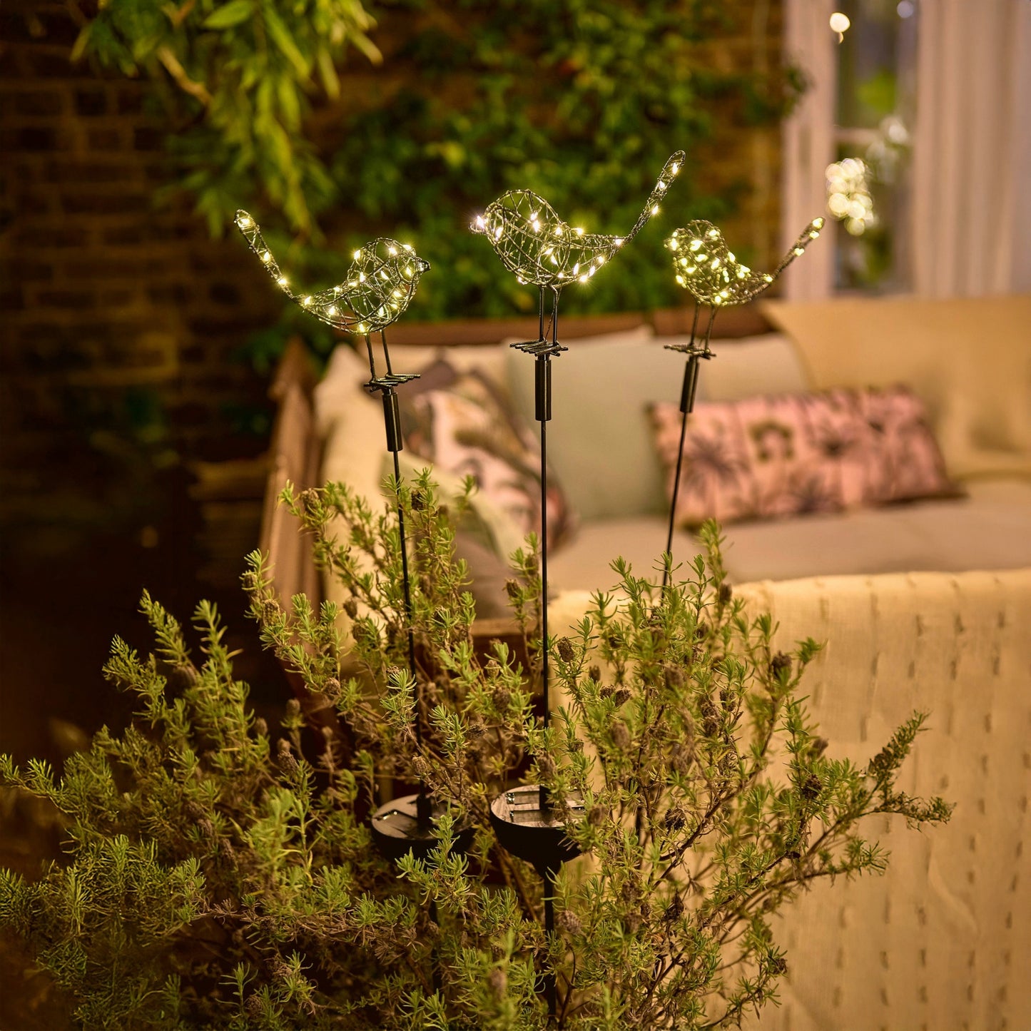 h potter solar sparrows staked in a garden planter on a patio