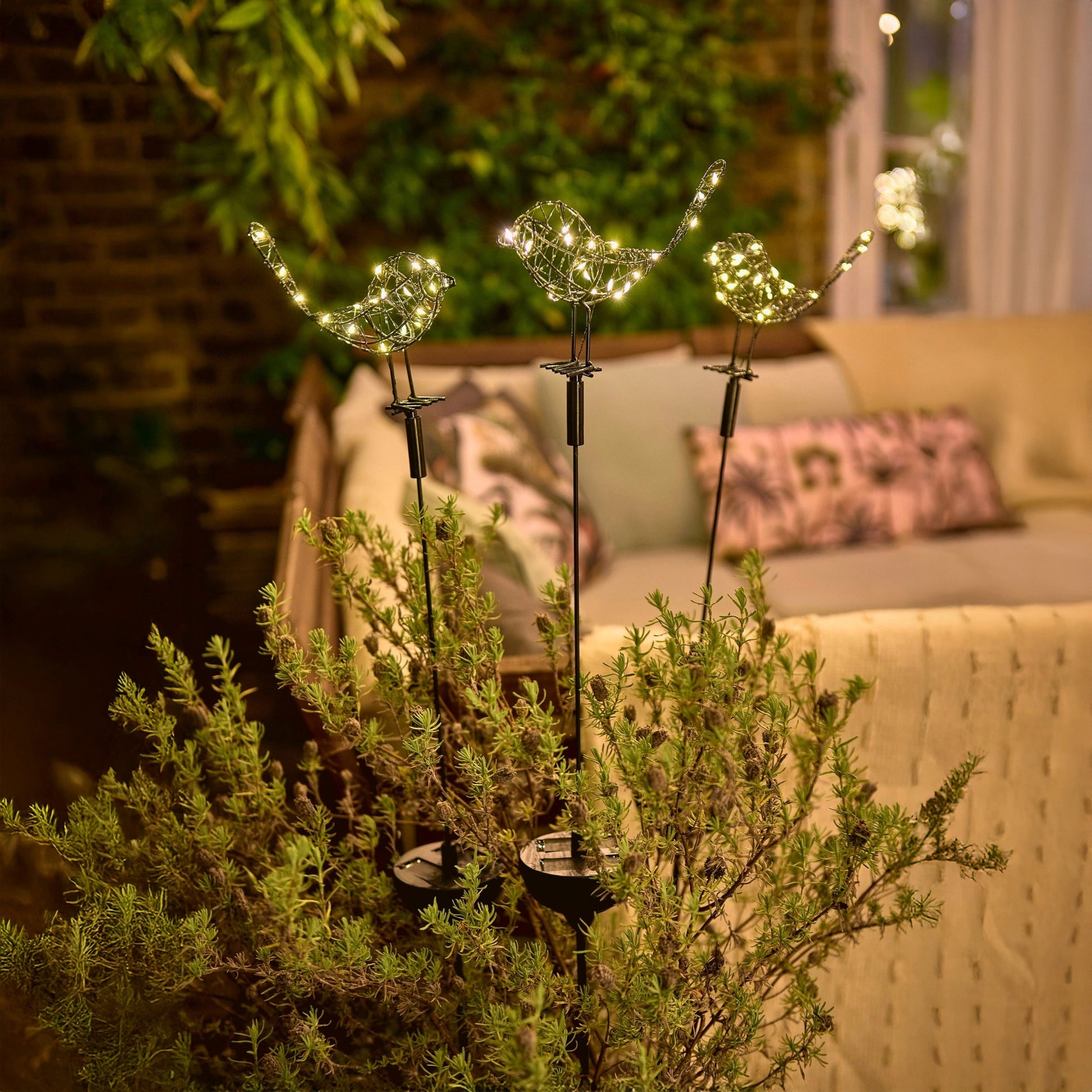 h potter solar sparrows staked in a garden planter on a patio