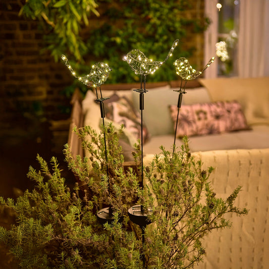 h potter solar sparrows staked in a garden planter on a patio