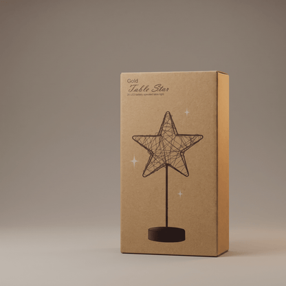 A rectangular kraft paper box standing upright on a neutral gray studio background. The box is labeled 'Gold Table Star' and features an illustration of a wire star on a stand with small starburst accents.