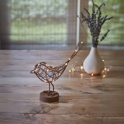 H Potter decorative metal bird with  led lights on a wooden surface with a blurred background