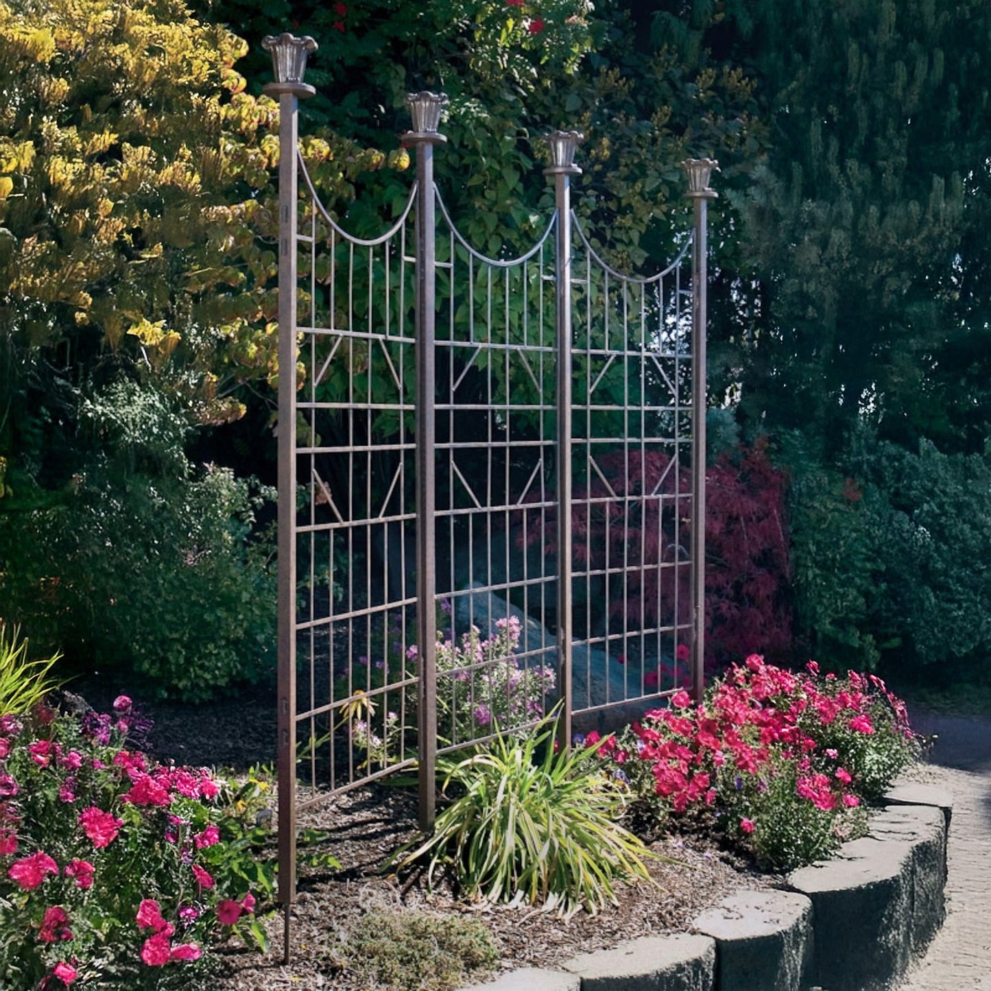 H Potter three-panel metal garden trellis screen in charcoal brown finish, freestanding in a landscaped garden setting